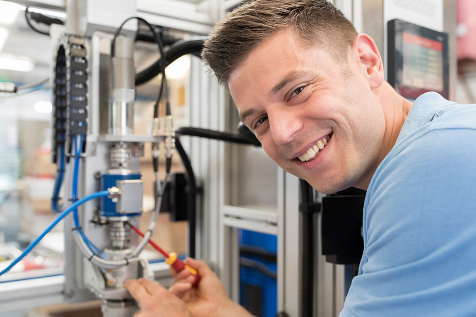 Portrait Of Male Engineer Working On Machine In Factory Mechatroniker/Mikrotechnologe